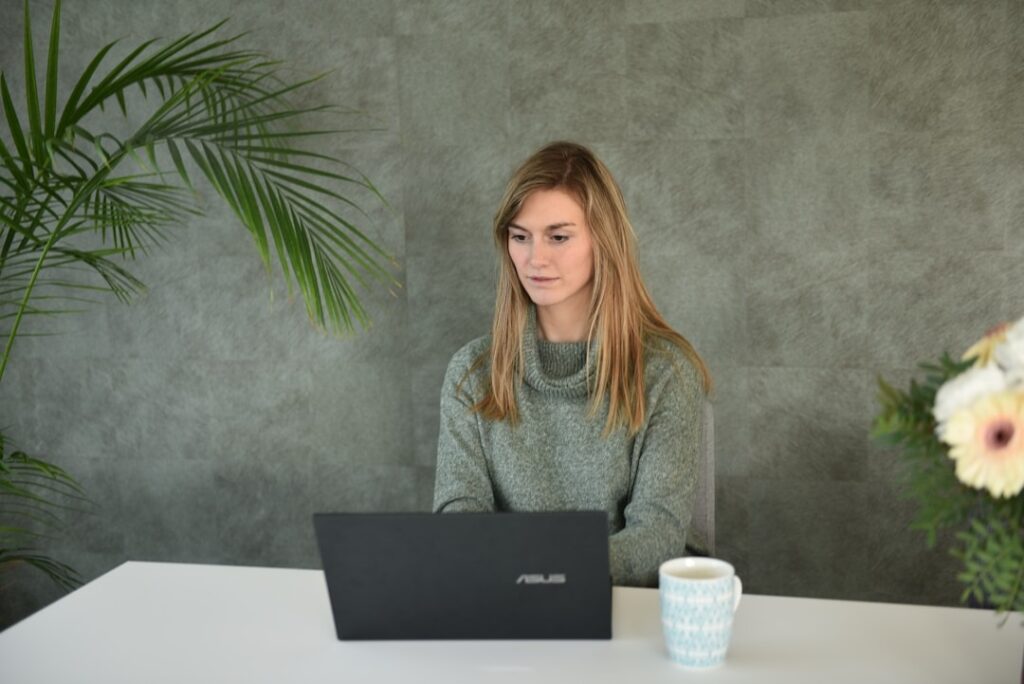 A woman at a table with a laptop, learning how to use a self-service knowledge base.